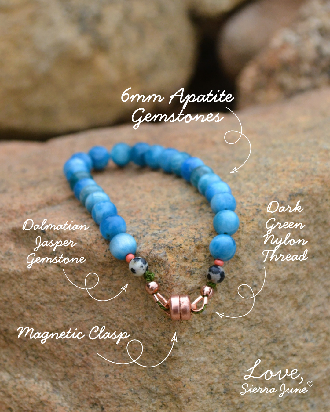 A beaded bracelet made of blue apatite gemstones with dark green nylon thread, a dalmatian jasper gemstone, and a rose gold magnetic clasp, displayed on a rock with handwritten text labels.