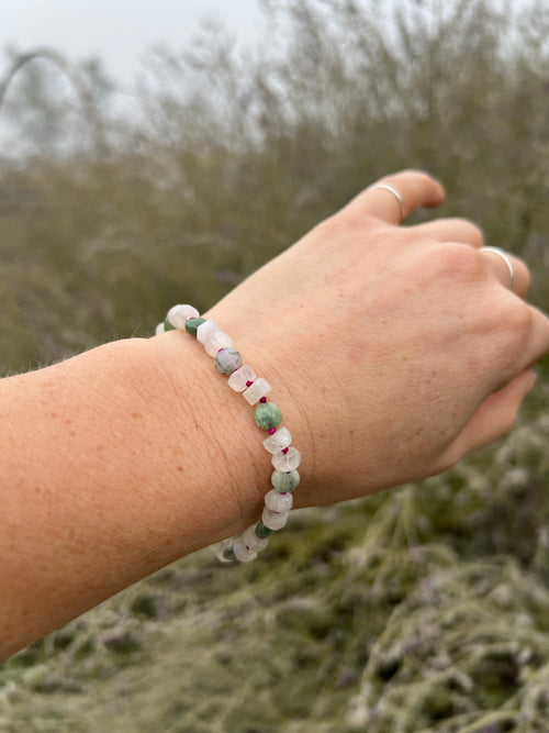 Hand wearing a beaded bracelet with a natural background